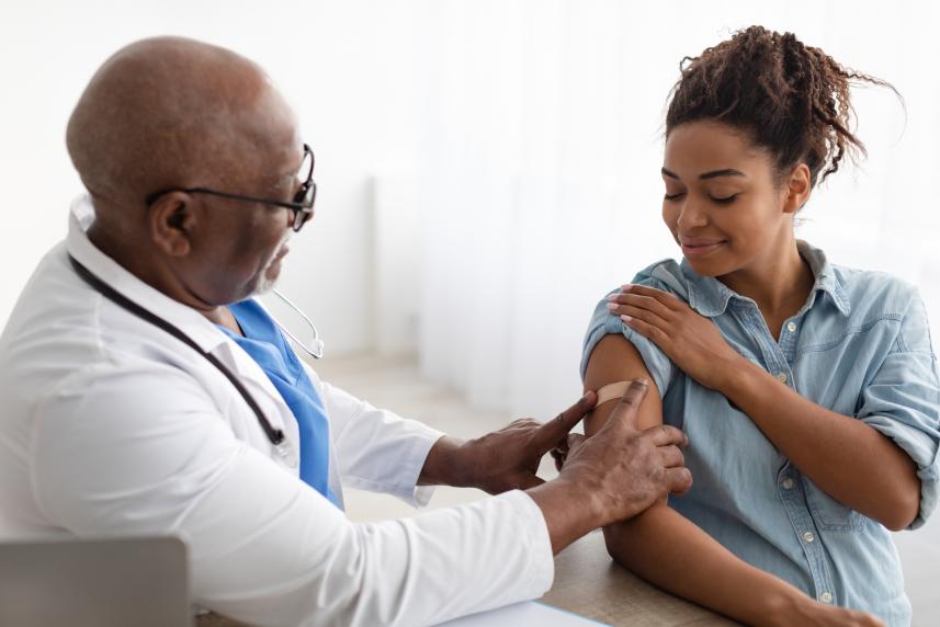 A doctor bandages a woman's arm after giving her an immunization