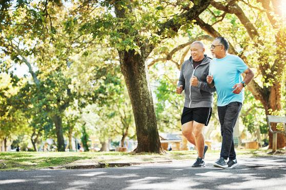 Two men running side by side at a park